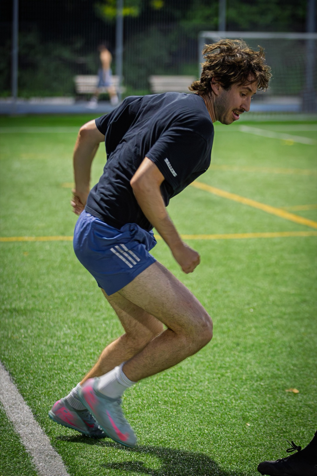 Coach Sam sprinting across a turf field mid-training